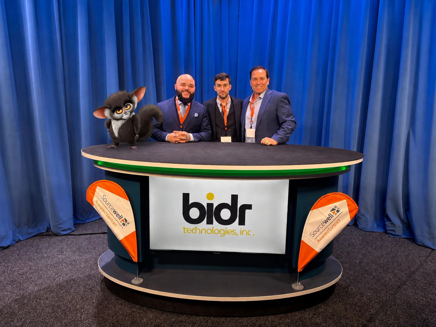 The BIDR Technologies team standing behind a BIDR-branded desk at a Sourcewell event